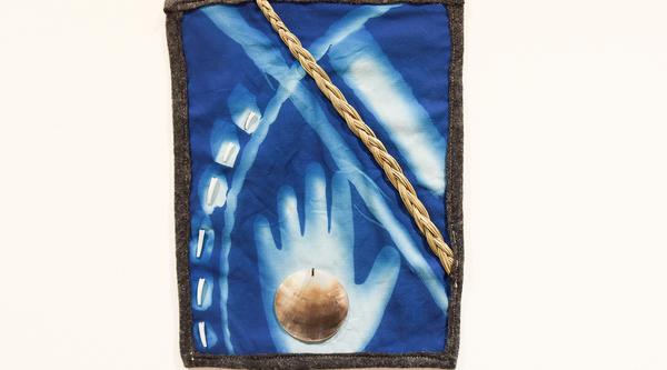 A cyanotype print with a hand, small shells and a seashell.