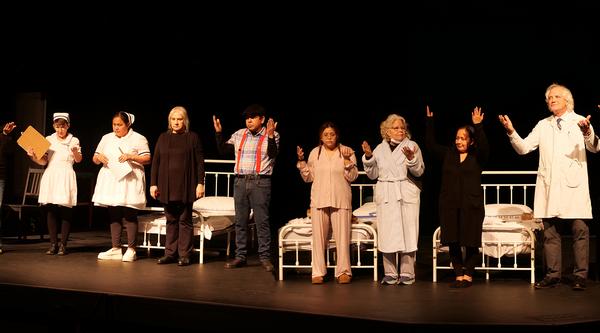 10 actors raise their hands in gratitude on a stage.
