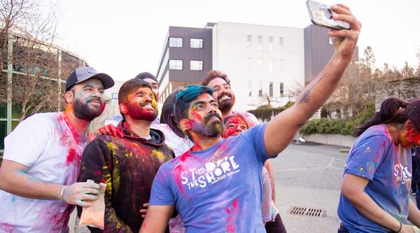 A group of students with coloured chalk on them pose for a selfie
