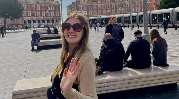 Jenna waves at the camera in a square