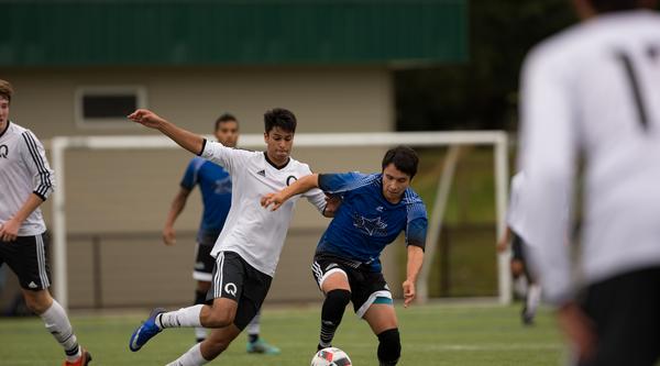 Mateo in the blue shirt runs down a soccer field with the ball pursued by an opposing player