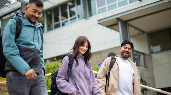 three students walking down the stairs in front of the VIU library.