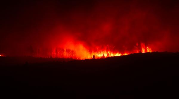 A wildfire burns over a ridge at night