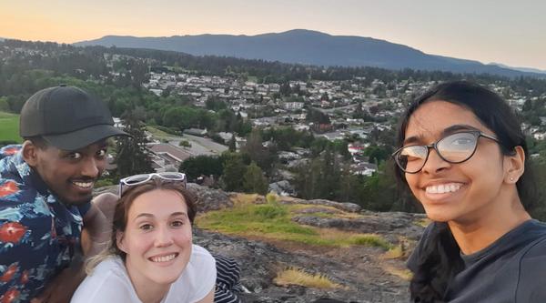 three students pose with the city of Nanaimo in the background