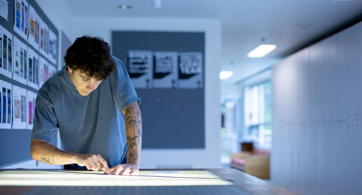 Ronin Carver works at a table in a graphic design classroom at VIU.