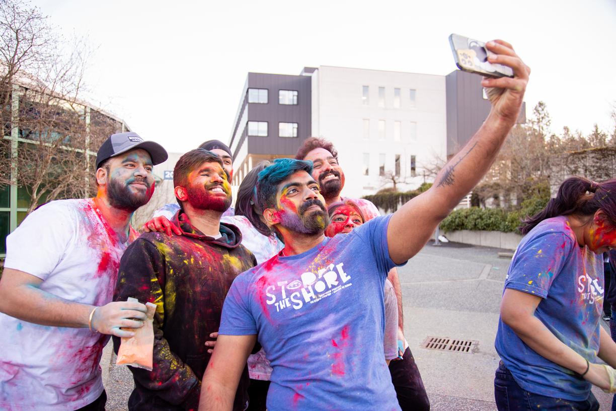 A group of students with coloured chalk on them pose for a selfie