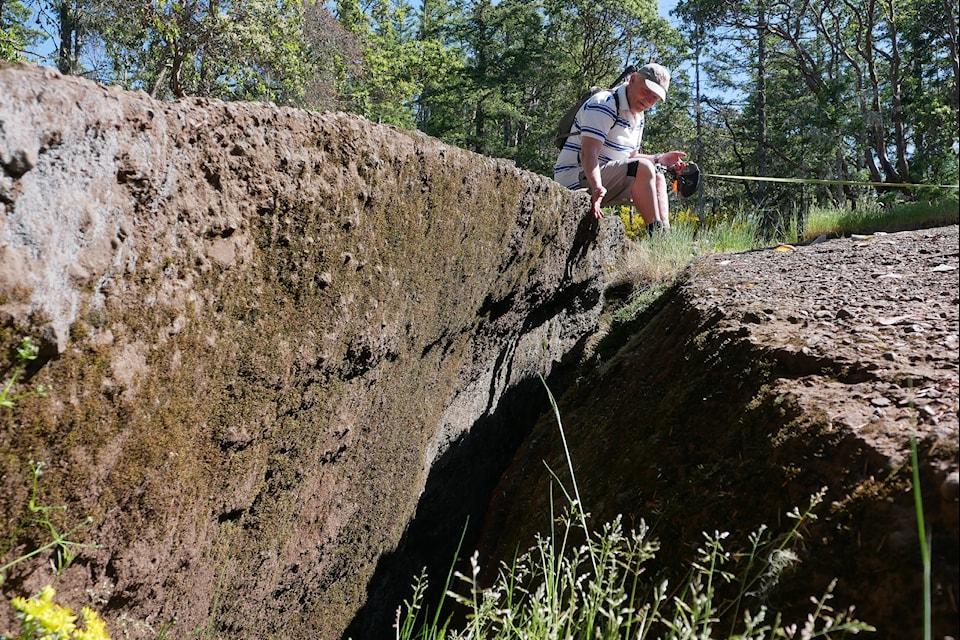 A man sits and observes a large crack in the ground