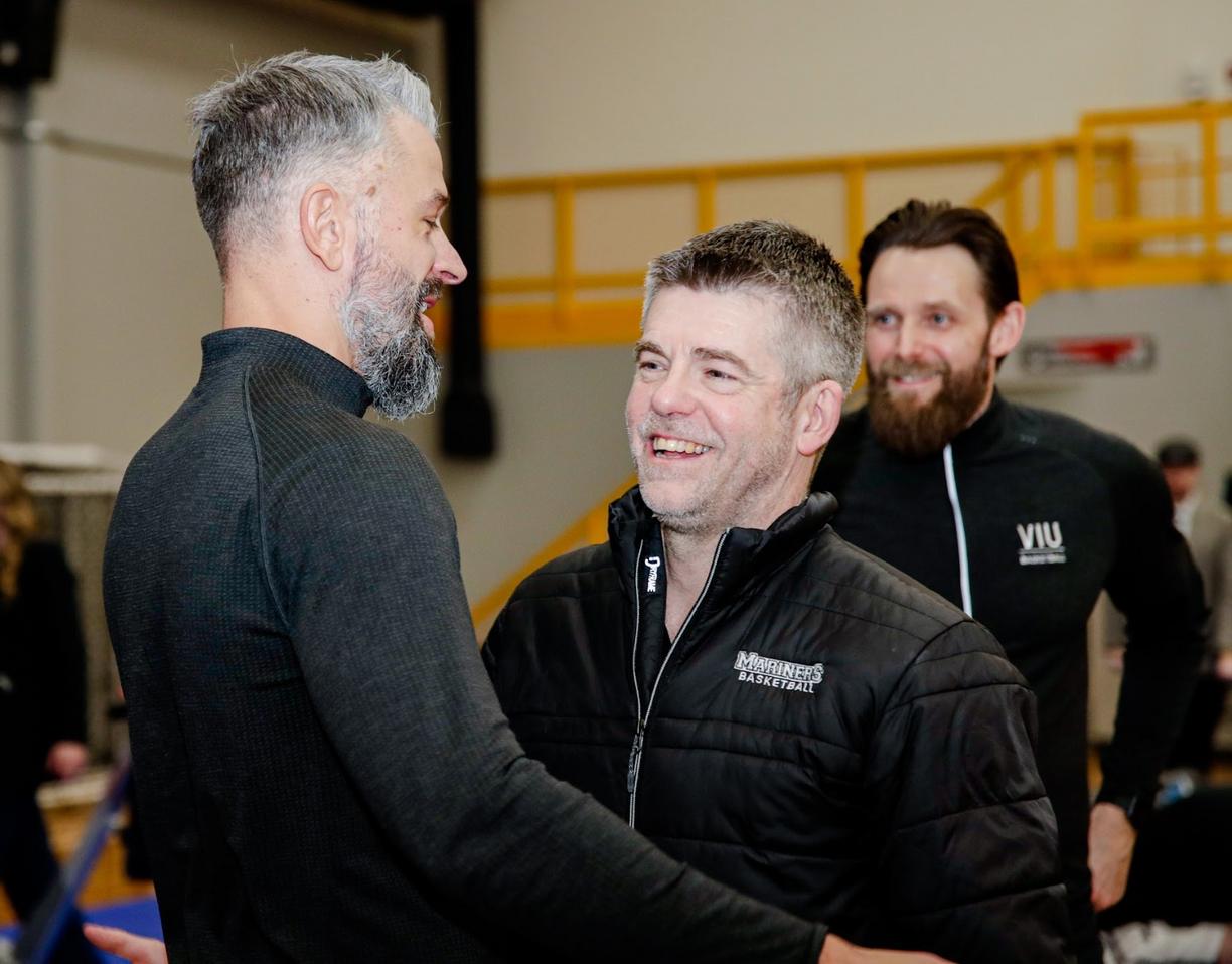 Two coaches lean in for an embrace