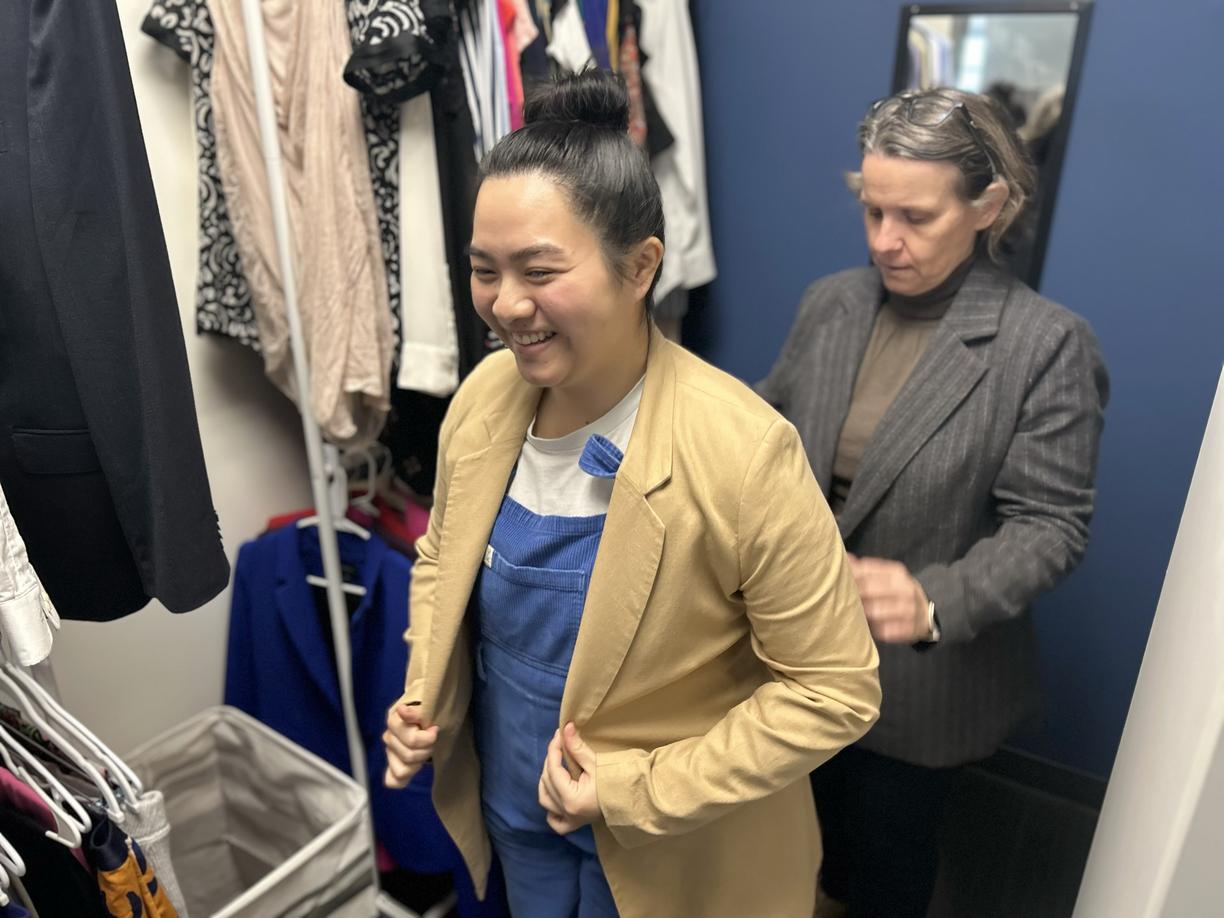One woman helps another try on a blazer