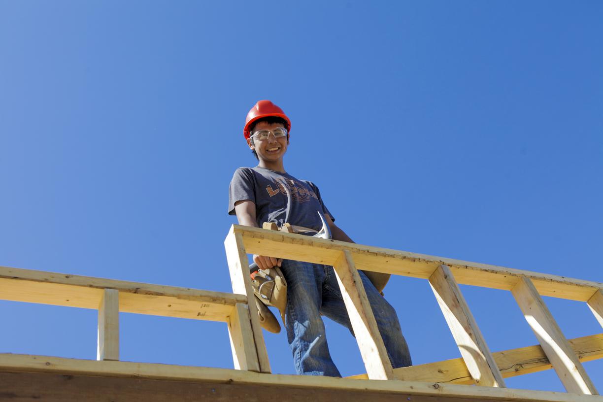 A carpenter up high building a frame