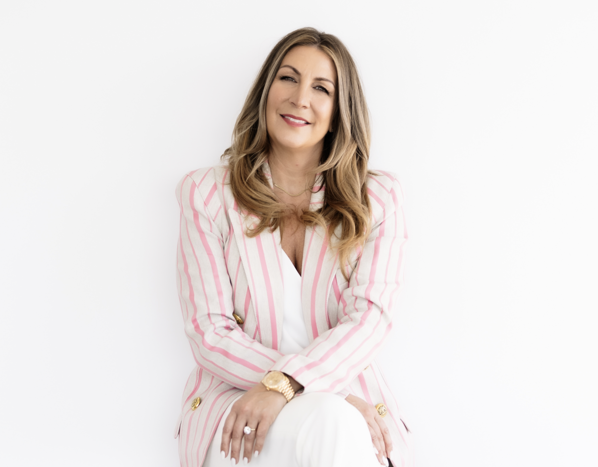 Jane Stoller sitting down against a white backdrop and smiling at the camera.