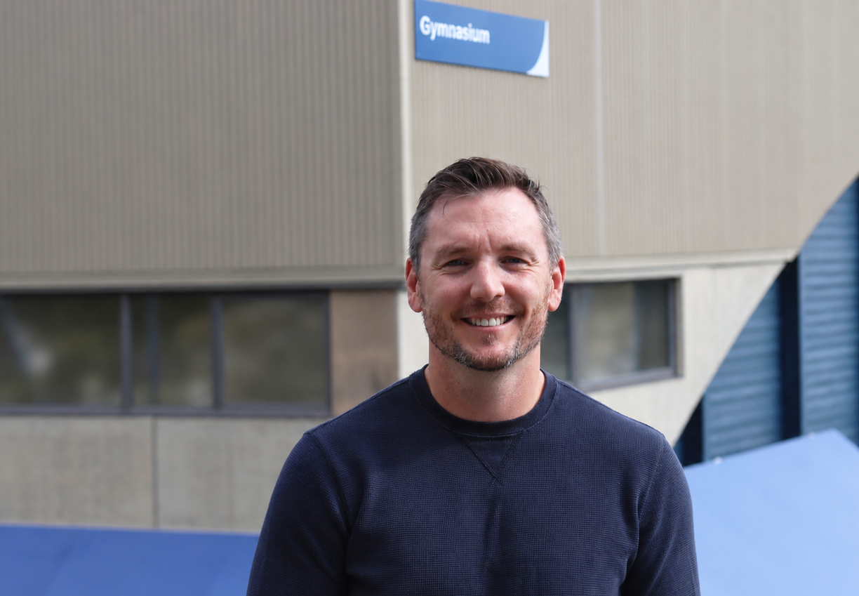 Jordan Herbison standing outside the VIU gym in a sunny day and smiling.