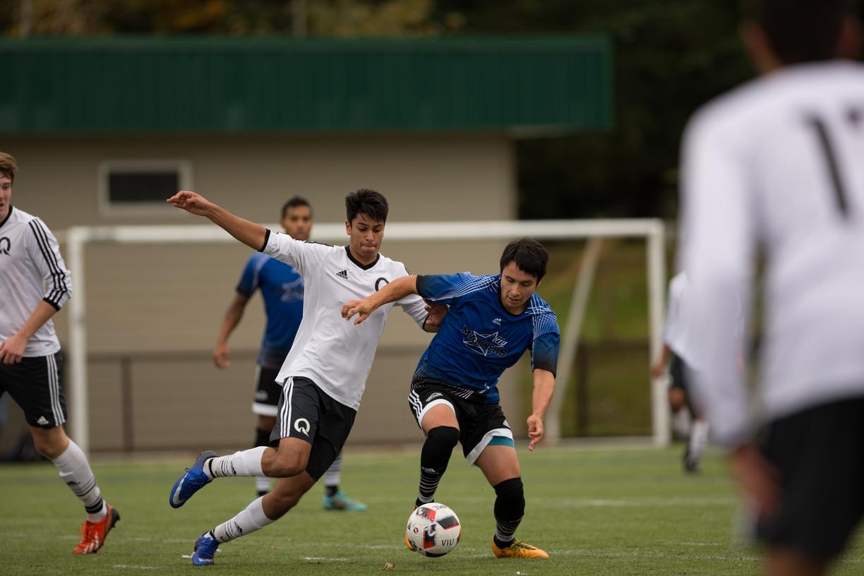 Mateo in the blue shirt runs down a soccer field with the ball pursued by an opposing player