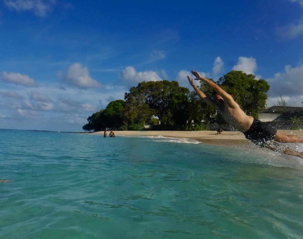 a person jumping into a very blue-green ocean