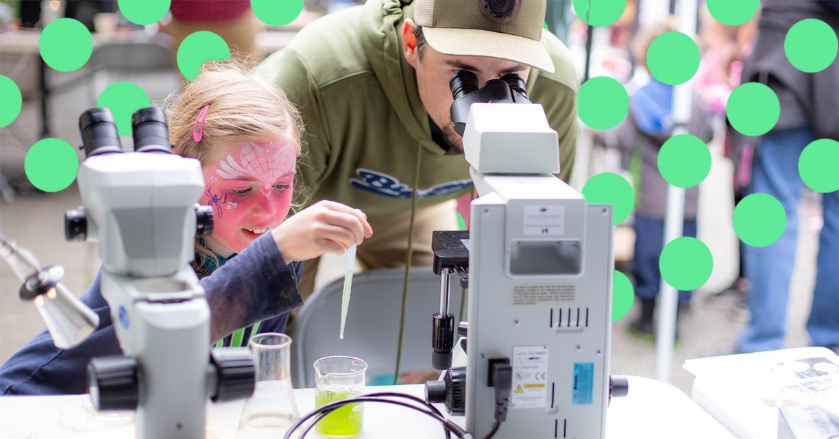 A dad and his daughter look into a microscope