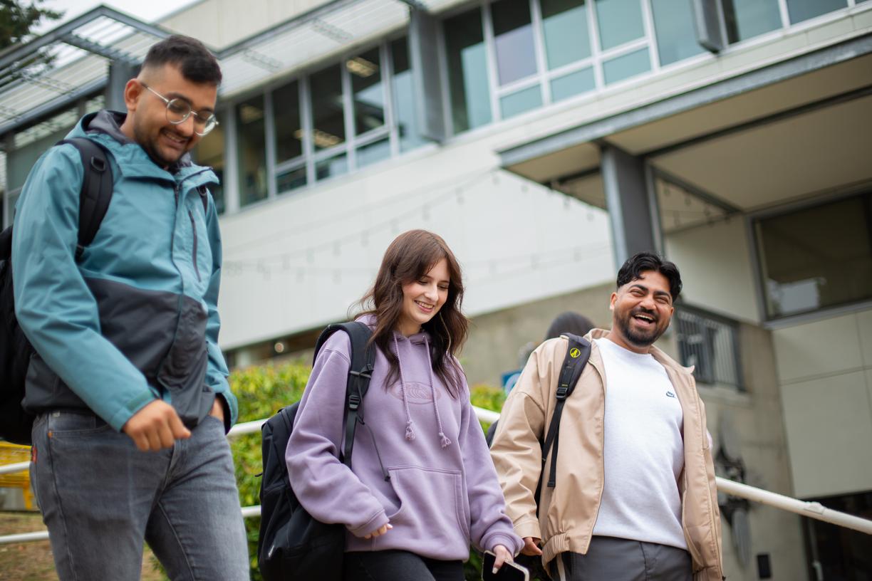 three students walking down the stairs in front of the VIU library.