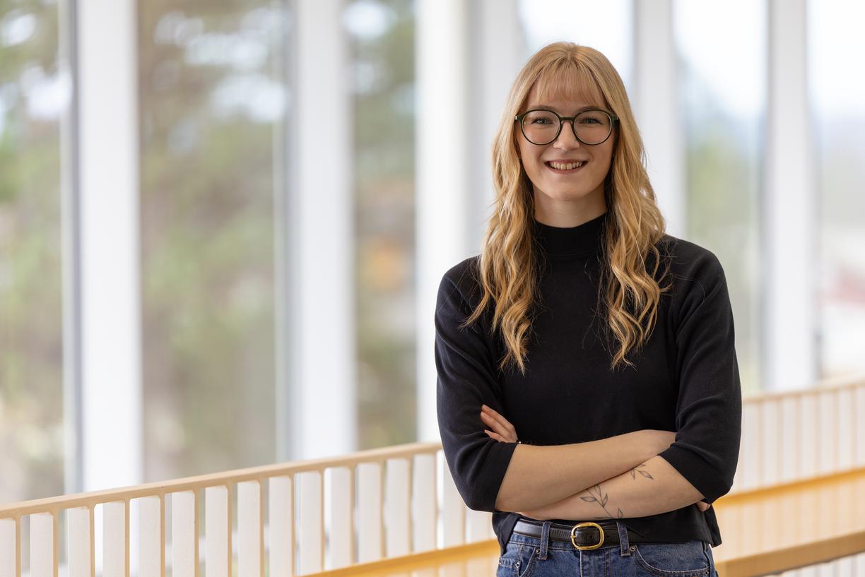 A student stands in front of a railing with her arms crossed