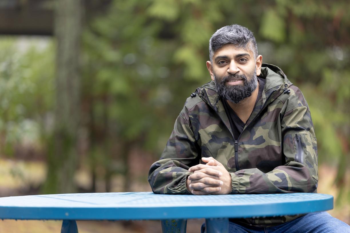 Harold Chandra sits at a blue table outside