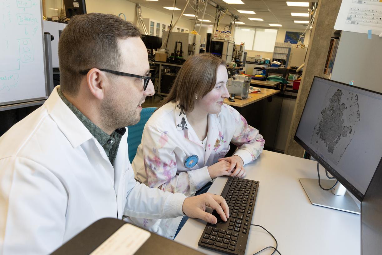 Kyle and Emily look at the image of a cancer tumour on a computer screen