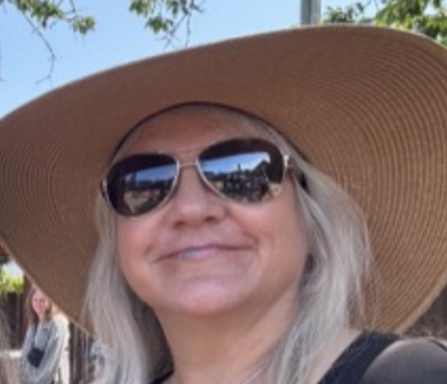 Ann Woodward smiling with sunglasses on.