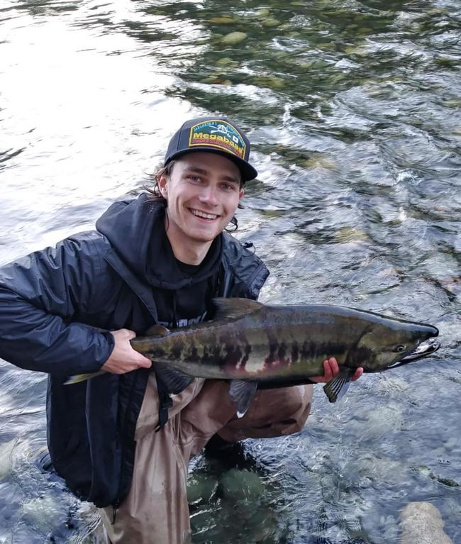 A man in a river holding a chum salmon