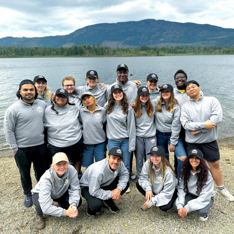 student residence team members having out at the beach in front of a lake on a cloudy day