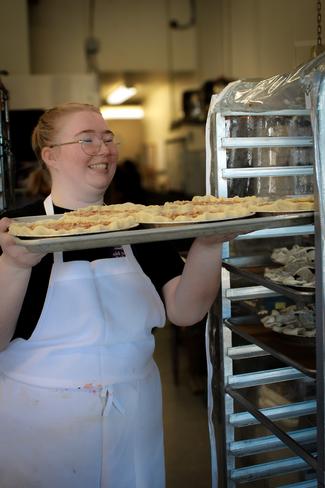 A pastry chef loading a tray of desserts onto a rack