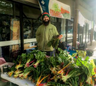 Katimavik volunteer Renard Souciant selling produce at VIU Farmers Market Planting Vegetable Seeds for a Growing Need