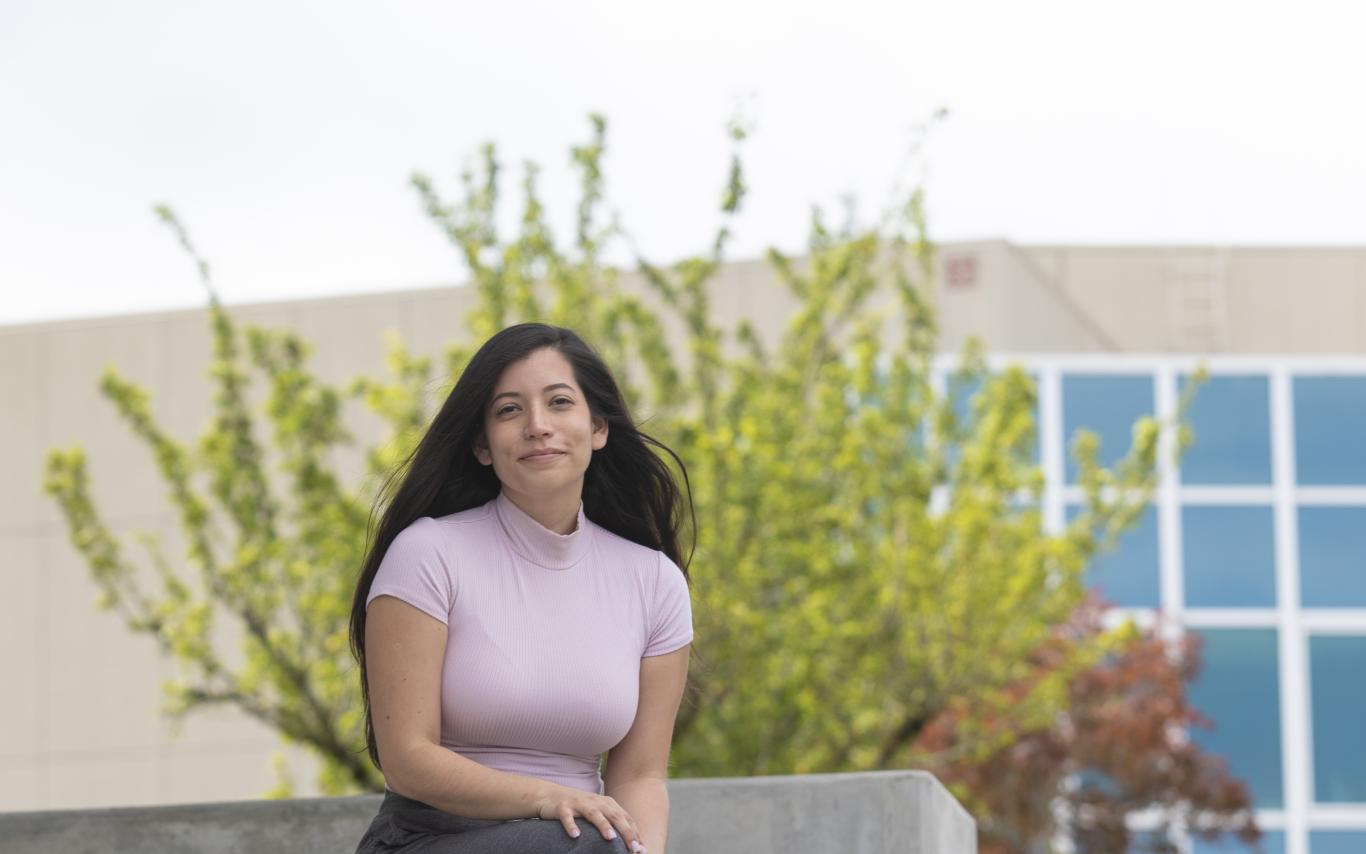 Student sitting on stairs, smiling at camera