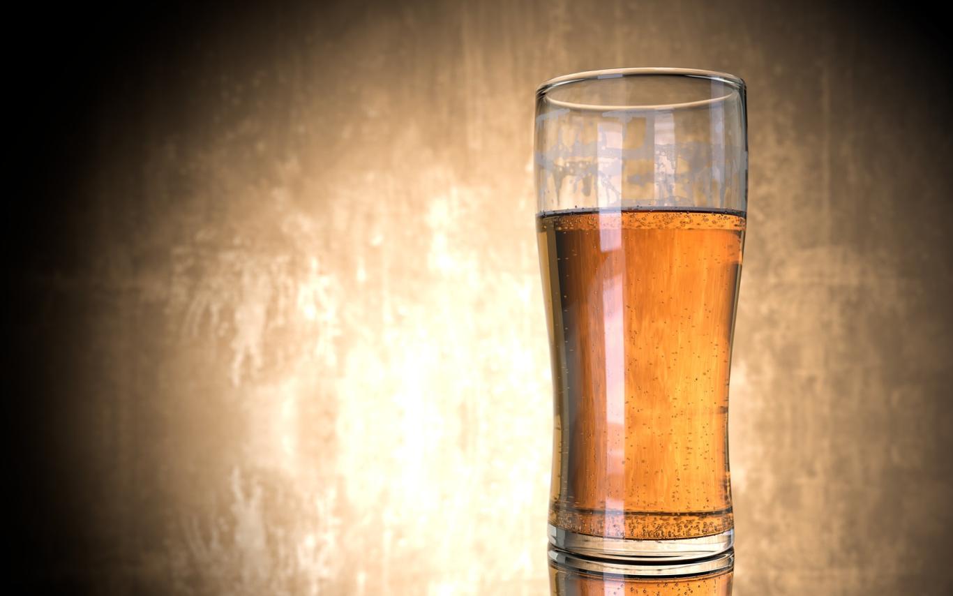 A glass of beer on a table in front of a tan an black background. Image featured in Dr. Marie Hopwood, VIU Department of Anthropology, Archaeology Beer blog