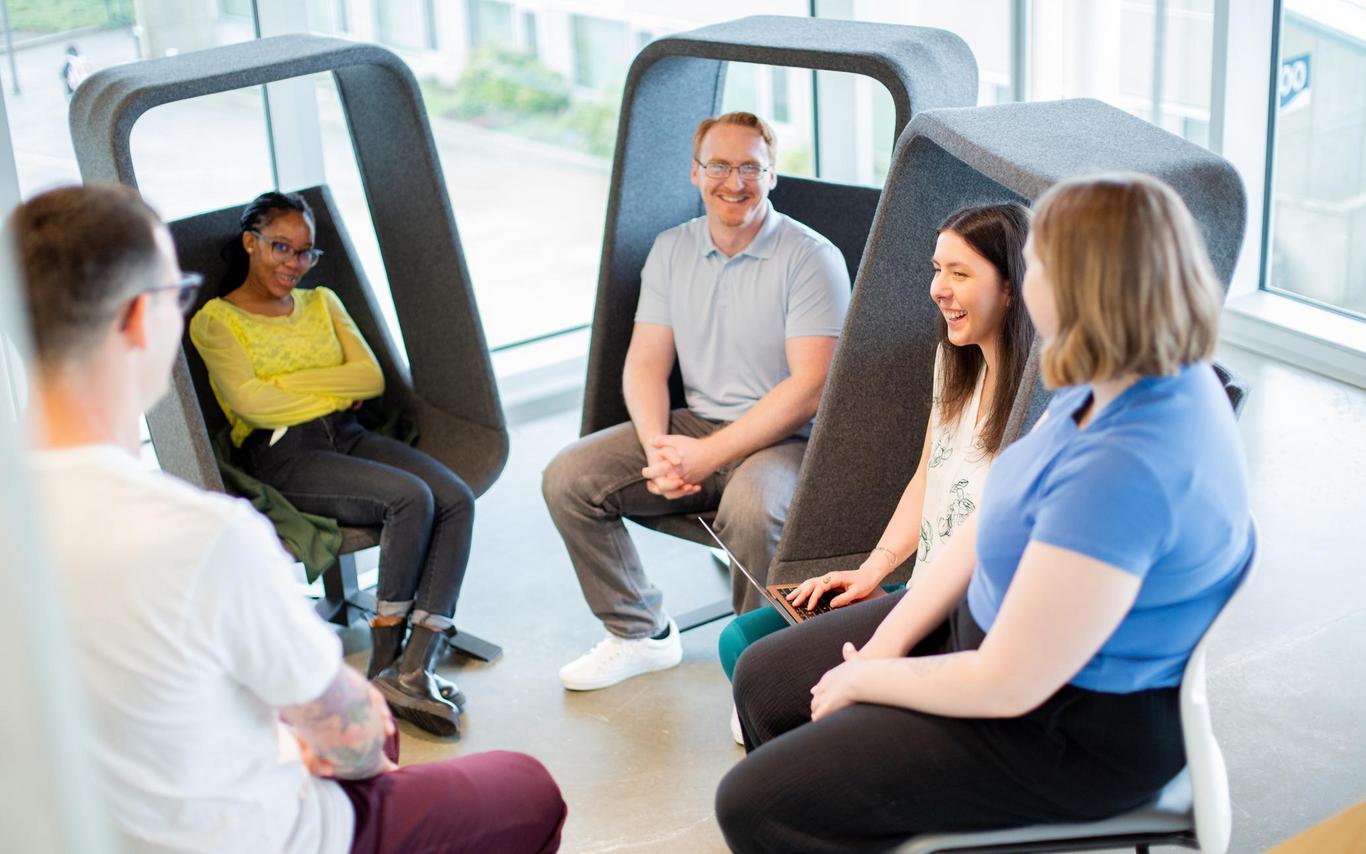 A group of students sits in cool chairs talking with each other