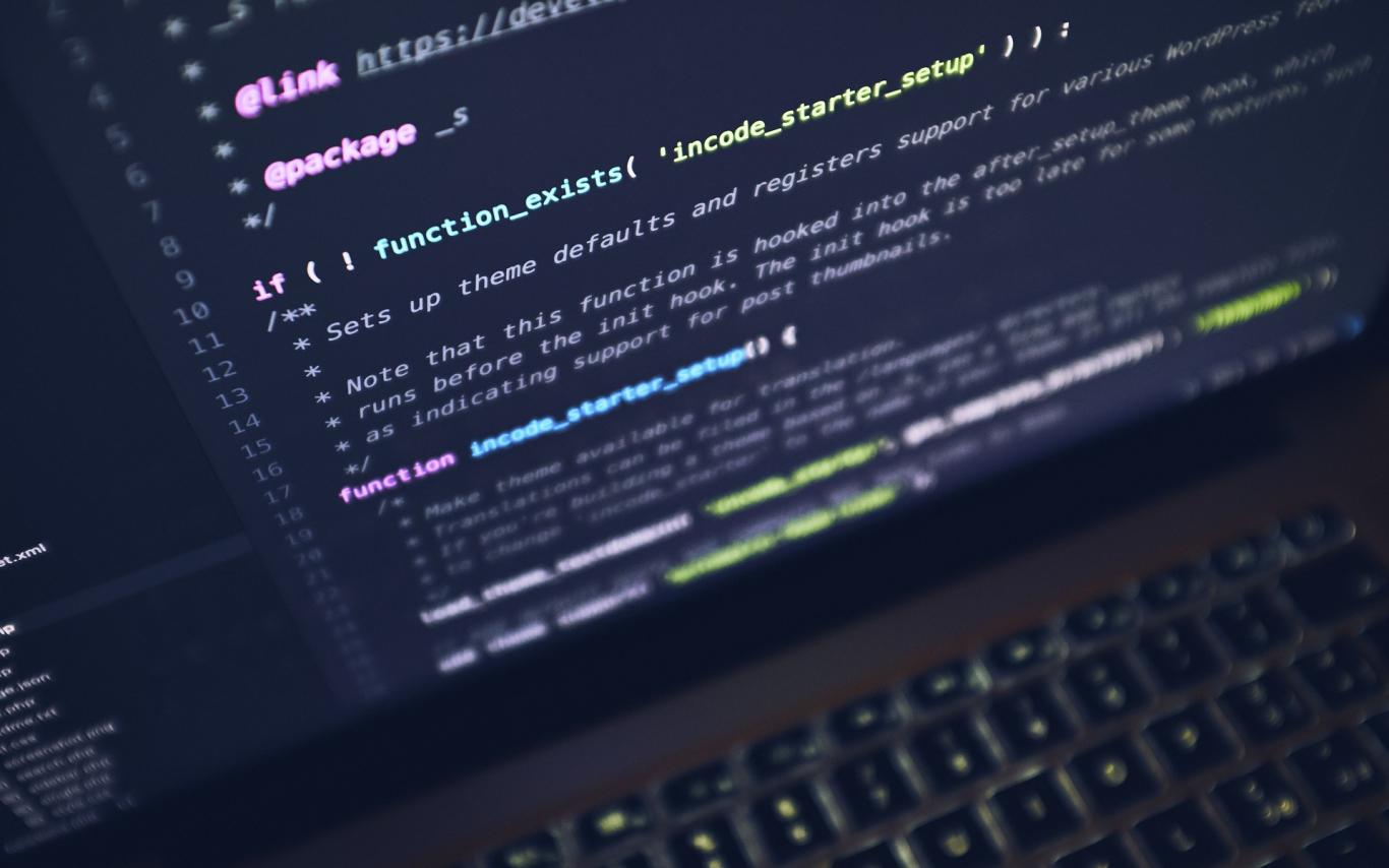 Close up of a black laptop with computer coding language on the screen.