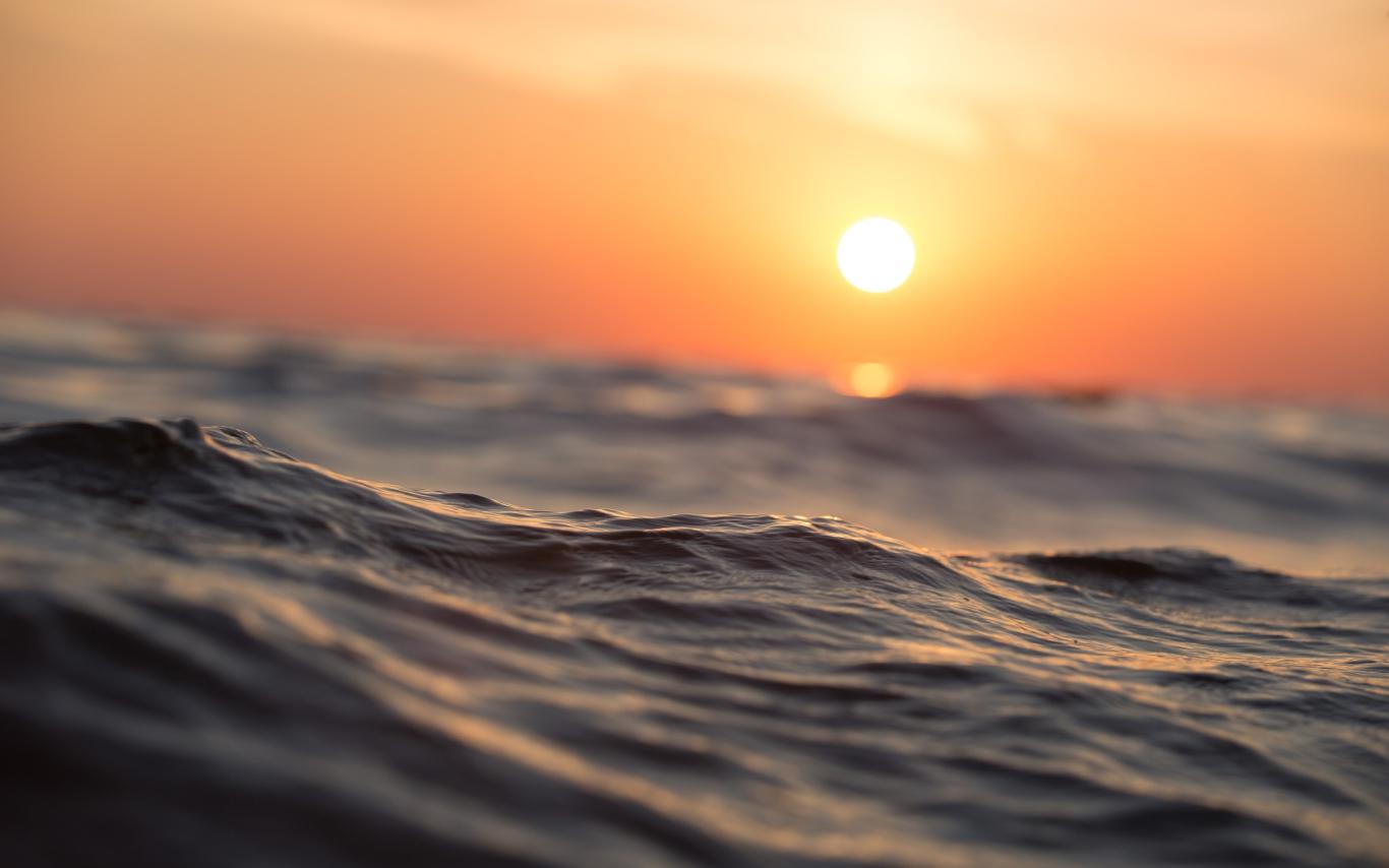 An orange and yellow sunset above ocean waves.
