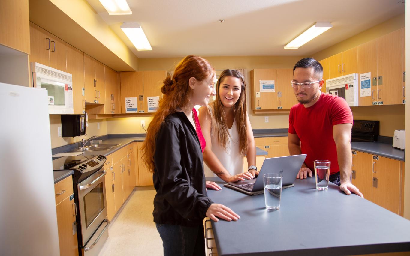 Three students standing around a kitchen island