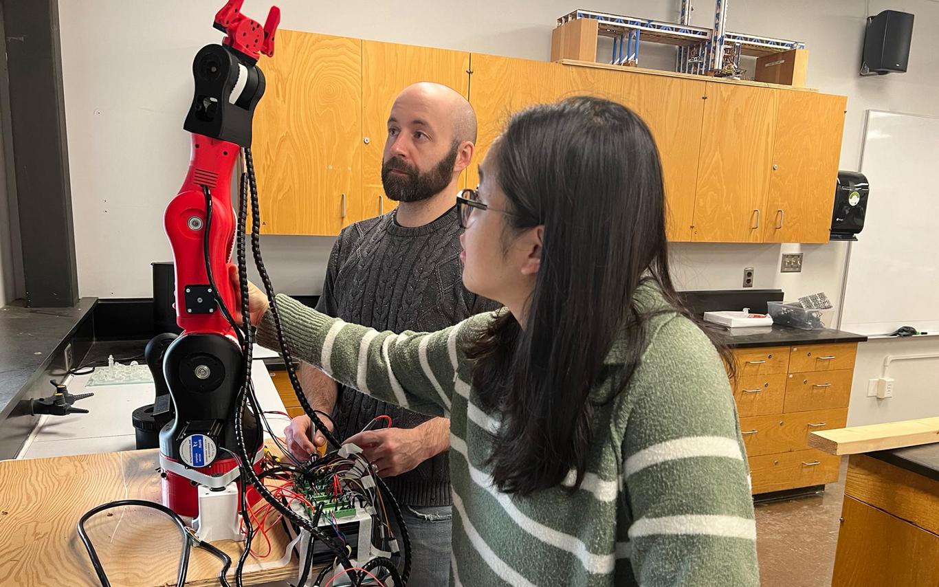 Dr. Xueling (Julie) Luo and Devin Ayotte adjust an 3D robotic arm.
