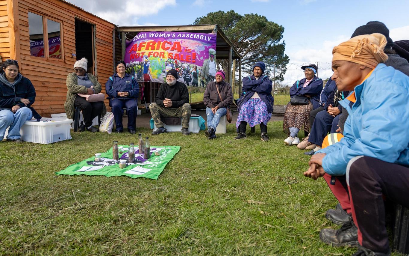 People sit in a circle with a banner behind them that reads Africa is not for sale.