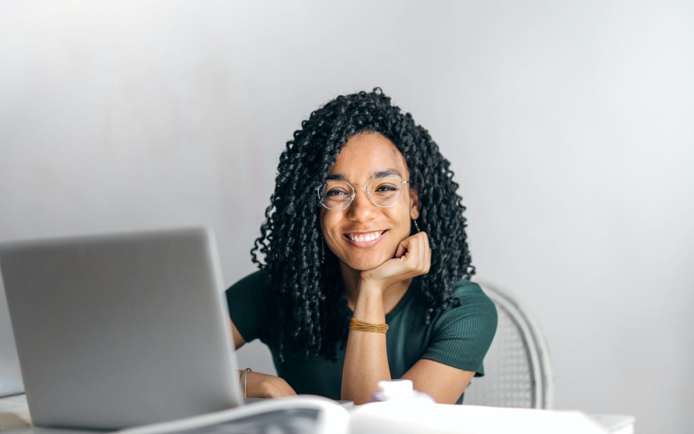 Girl looking up from laptop and smiling at the camera