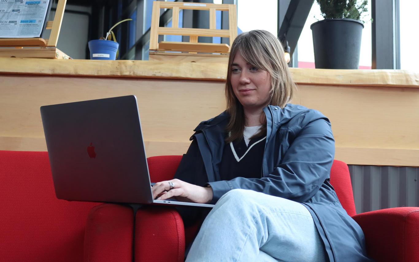 Young woman sitting on a red couch looking at a laptop