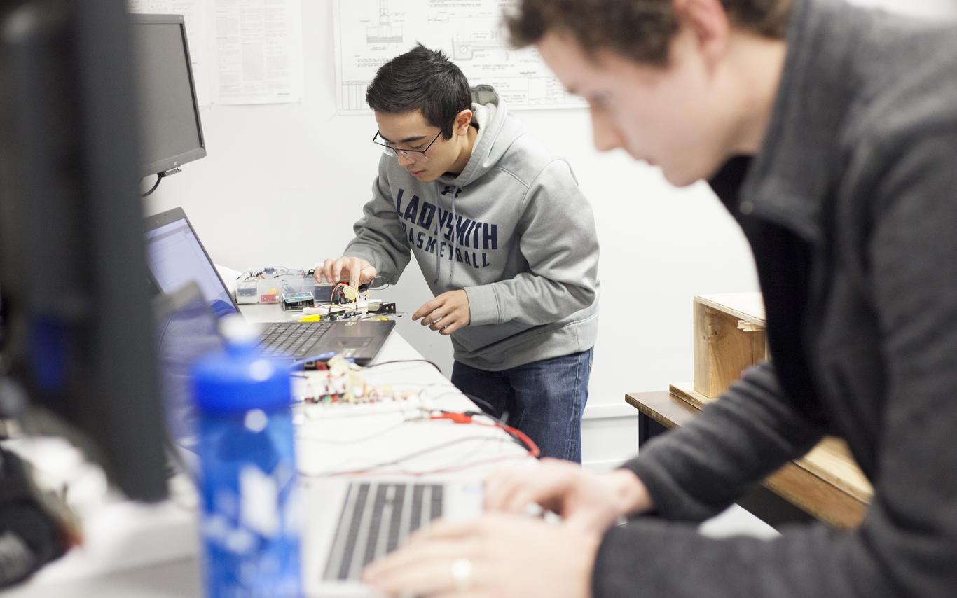 Two VIU Engineering students work on computer equipment in a lab.