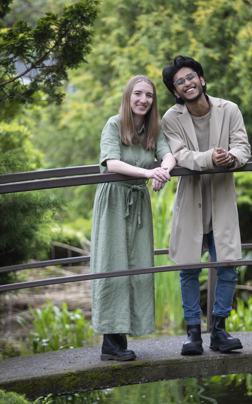 Lauryn Mackenzie and Siddhanth Arikari stand together on a bridge overlooking a koi pond.
