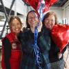 Three women stand with red balloons in support of Giving Tuesday