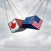 Two freight containers swinging into each other, one has the Canada flag, the other has the United States flag