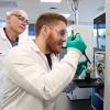 Dr. Chris Gill observes as Lucas Abruzzi puts a sample in the mass spectrometer.