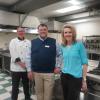 Three people stand in a culinary arts lab