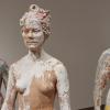 Three sculptures of a person splashed with white paint.