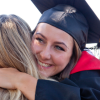 Student in grad cap hugs someone with words Giving Tuesday on side