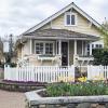 A building painted yellow with a white picket fence around it and a flower box with tulips out front.