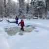 Children on a rink clearing the snow off