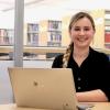 VIU Psychology student Cala Annala sitting at a desk with an open MacBook in front of her