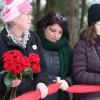 Eliza Gardiner holds a bouquet of red roses and stands next to Joy Gugeler and a student during the 2022 vigil.